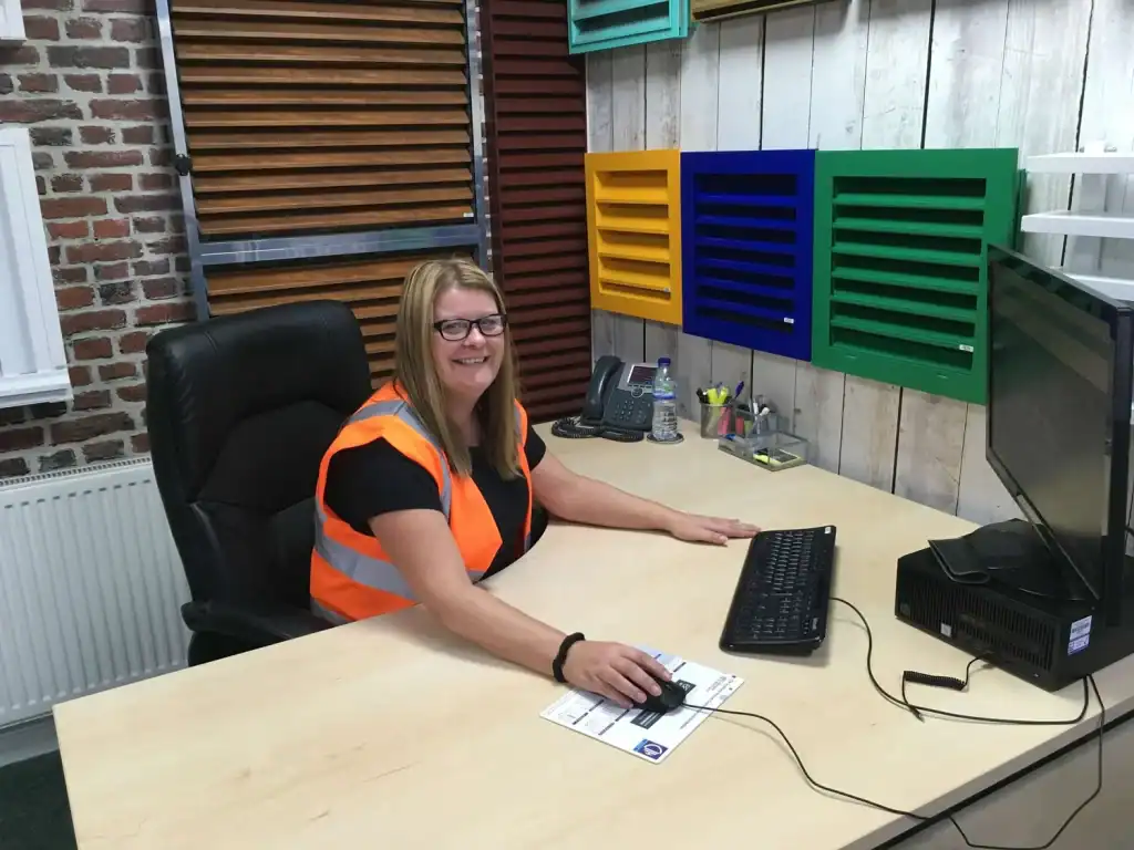 Kim Ellis, General Manager at IKON Aluminium Systems, seated at her desk with aluminium louvre samples displayed behind her