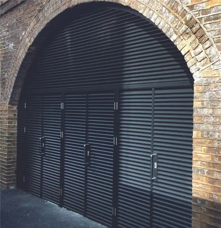 Custom arched aluminium louvre installation fitted within a brick archway opening