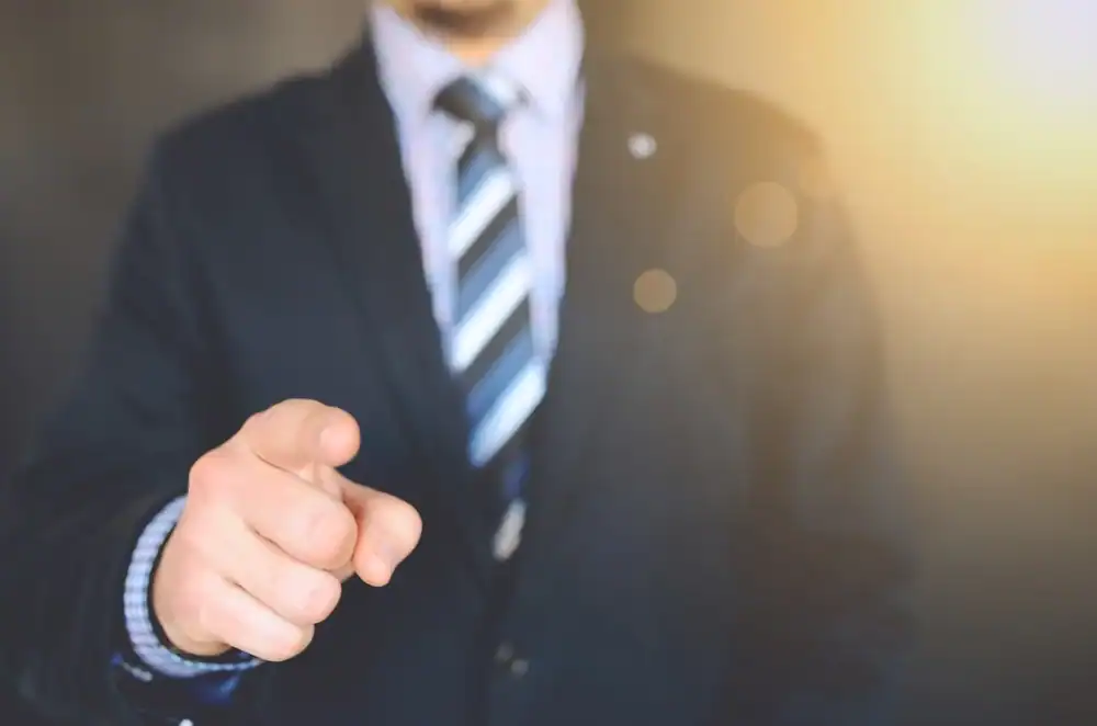 Business professional pointing towards the camera used to illustrate a new job post and vacancy announcement