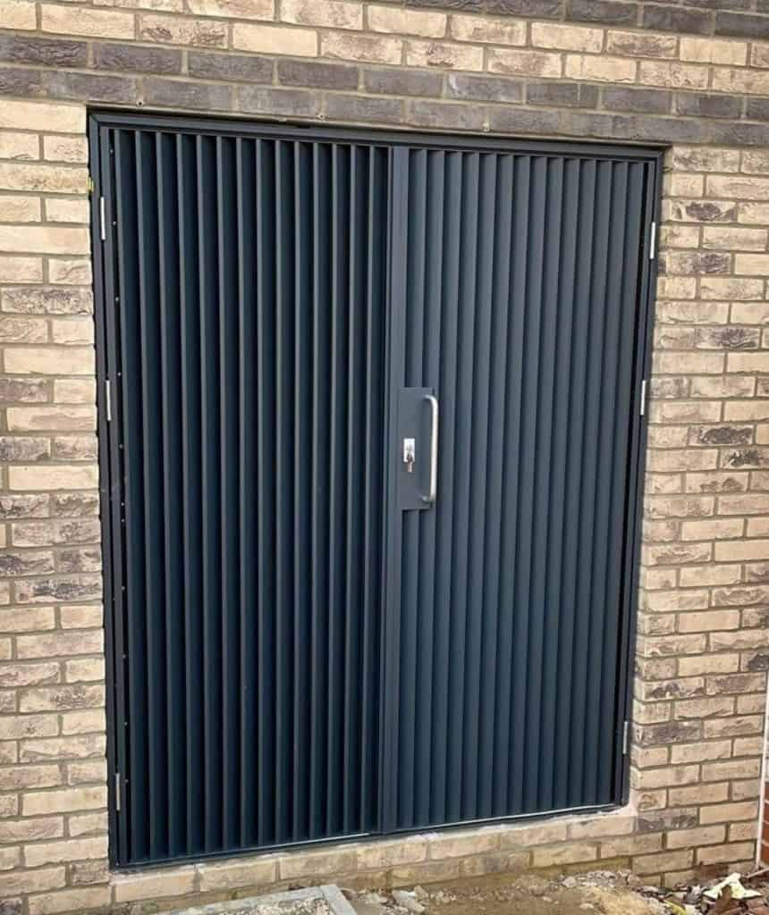IKL50 hinged door with vertical blades installed in a brick facade opening